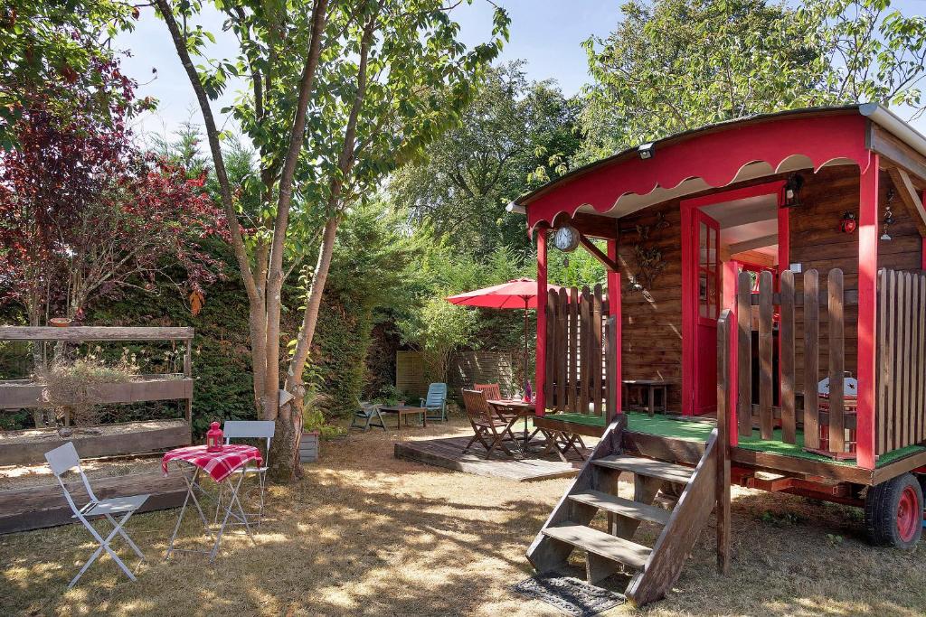 a small red house with a table and chairs at Roulotte Champêtre Bella in Brix