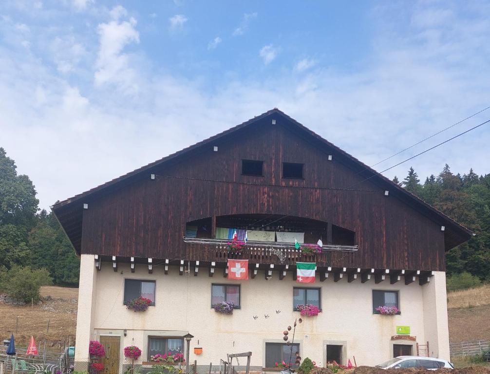a large barn with a gambrel roof at Chambres d'hôtes Petit Martel in Les Ponts-de-Martel