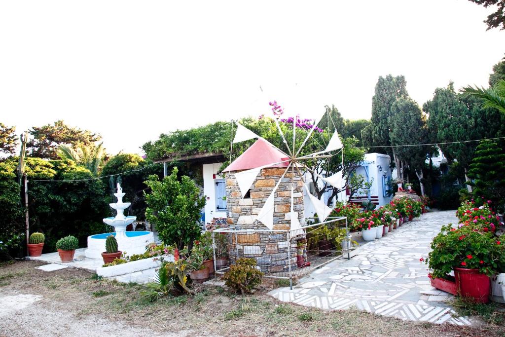 un jardín con una casa con una fuente y plantas en Prasino Oniro en Tinos Town