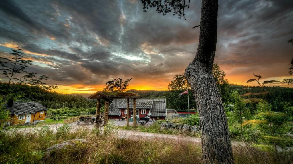 una casa en un campo con una puesta de sol en el fondo en Hagen, en Vennesla