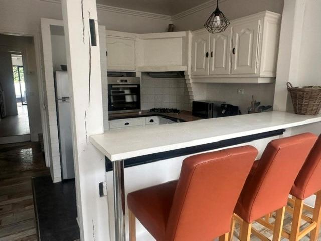 a kitchen with white cabinets and orange bar stools at Floc & Sens in Chalons en Champagne