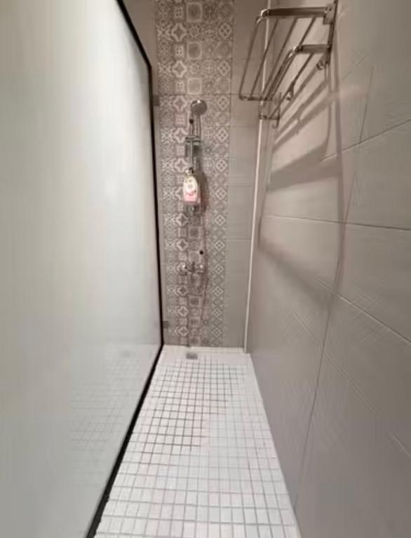 a shower in a bathroom with a tiled floor at Moon Homestay in Jincheng
