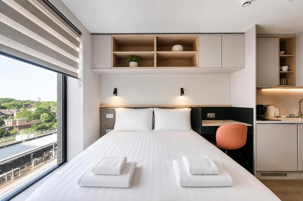 a bedroom with a large white bed with two chairs at Argyl - The Apiary, Ealing in Ealing