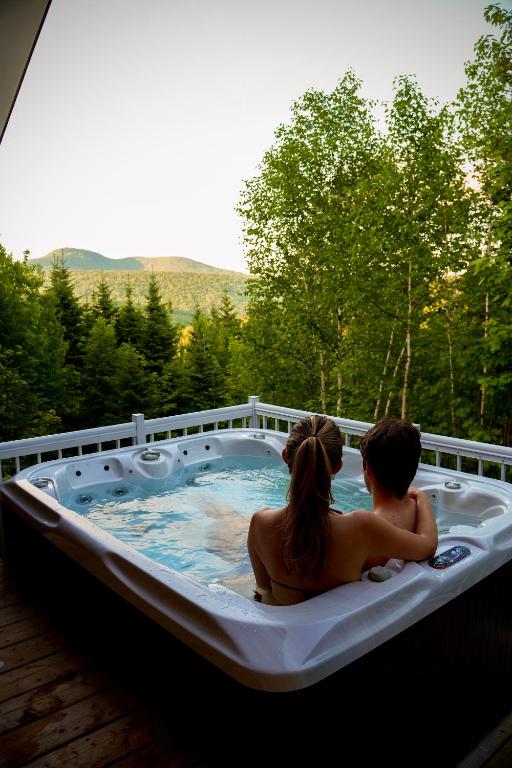 a man and woman sitting in a hot tub at Momentôm Refuges Nature in Petite-Rivière-Saint-François