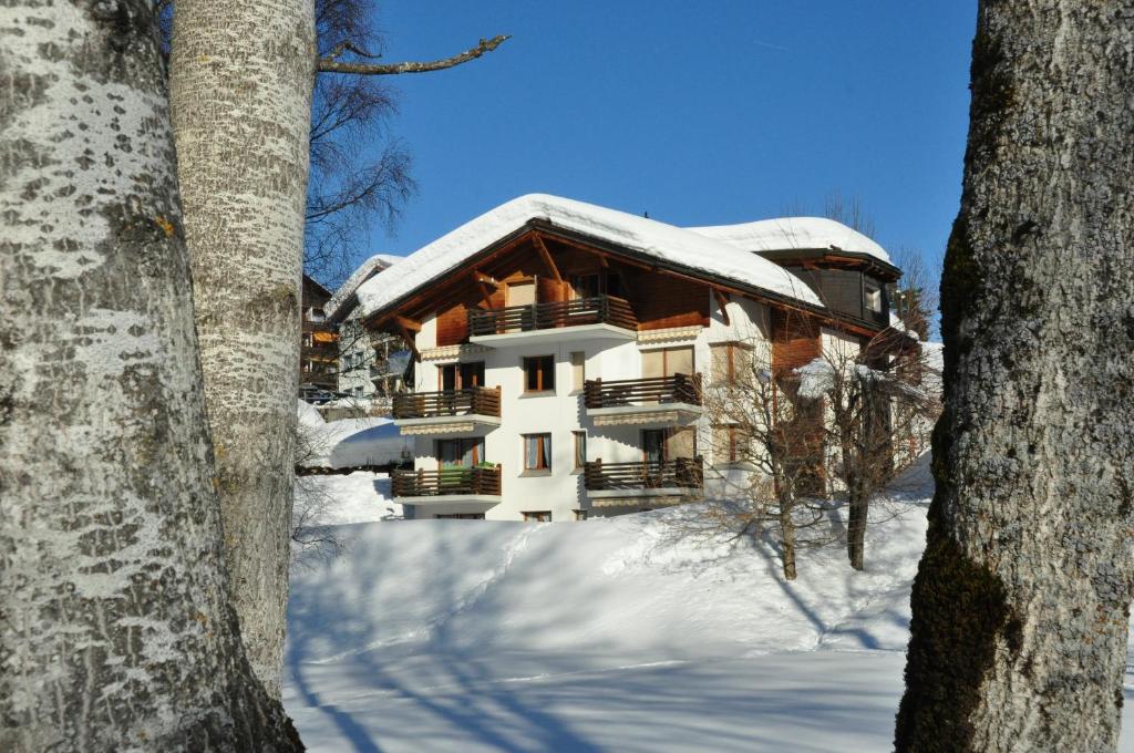 a building with snow on top of it at Casa al Lag - direkt am Laaxersee in Laax
