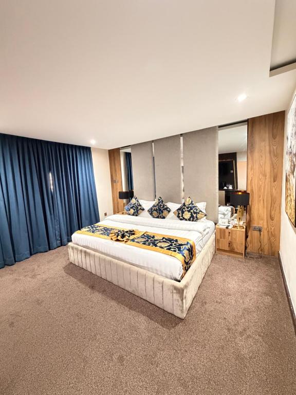 a large bedroom with a large bed with blue curtains at Sonia Hotel in Accra