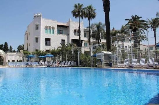 a large swimming pool with chairs and a building at Chaine ELDJAZAIR by HTT in Alger