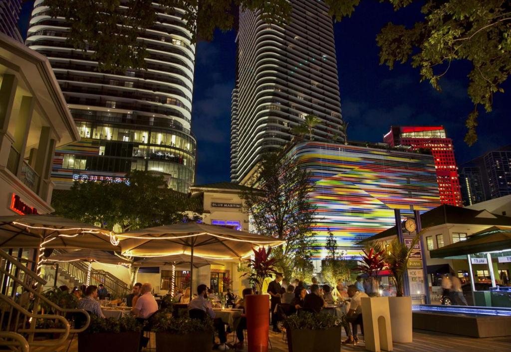 a city at night with tall buildings and people sitting at tables at Vibras Wellness in Miami