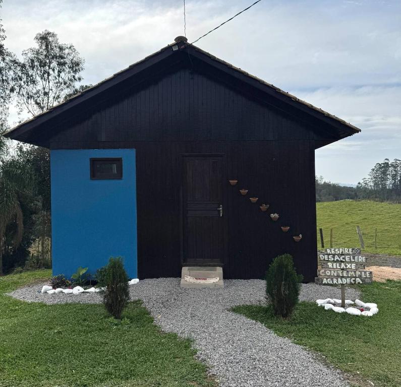 a black building with a blue door in a field at CABANAS BELVEDERE SERRA DO RiO DO RASTRO in Lauro Müller