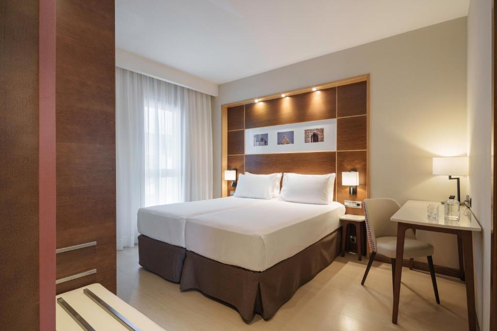 a hotel room with a bed and a desk and a table at Dorma León in León