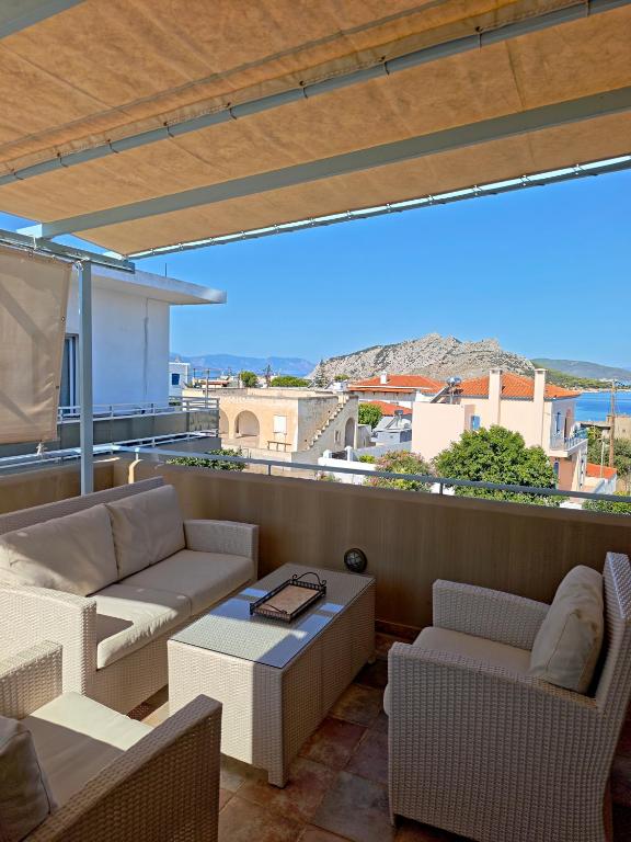 a balcony with a couch and chairs and a table at MONI apartment in Perdika