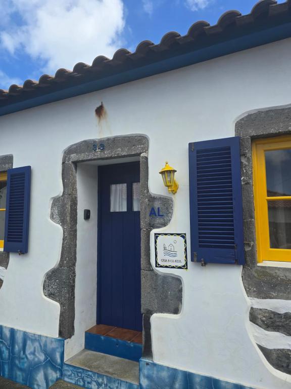 a house with a blue door and a yellow window at Casa Poço Azul in Achadinha