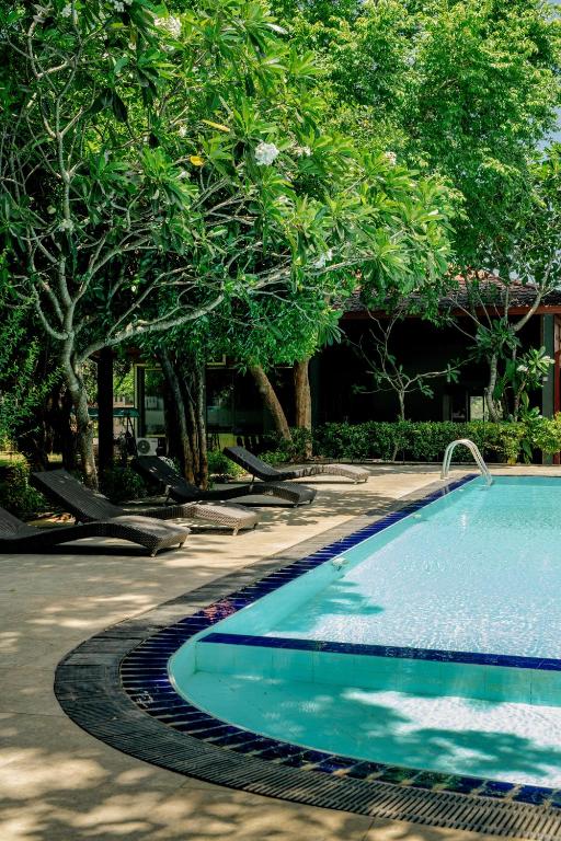 a swimming pool in a park with trees at Roy's Polonnaruwa in Polonnaruwa