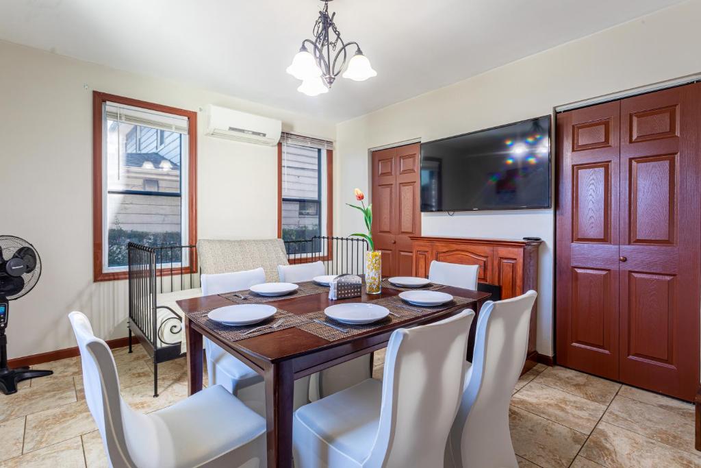 a dining room with a wooden table and white chairs at One Bus Stop to Time Square-4BR Duplex-Free Parking in Hillside