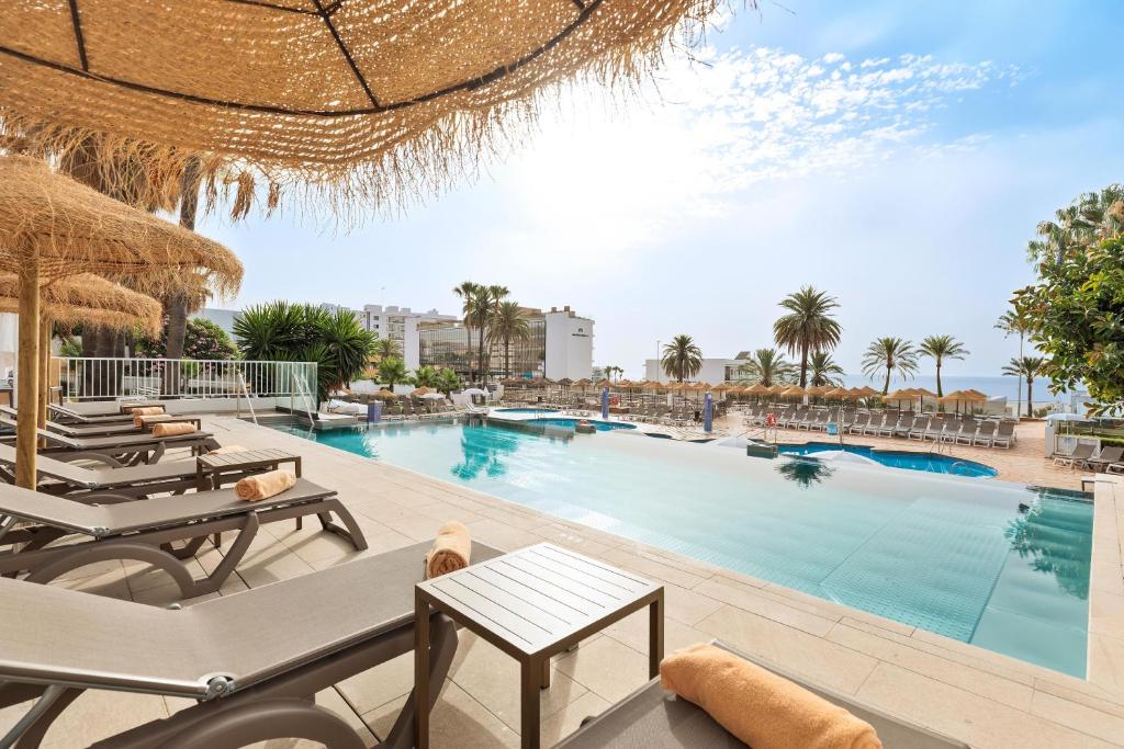 a large swimming pool with chaise lounges and chairs at Hotel Best Siroco in Benalmádena