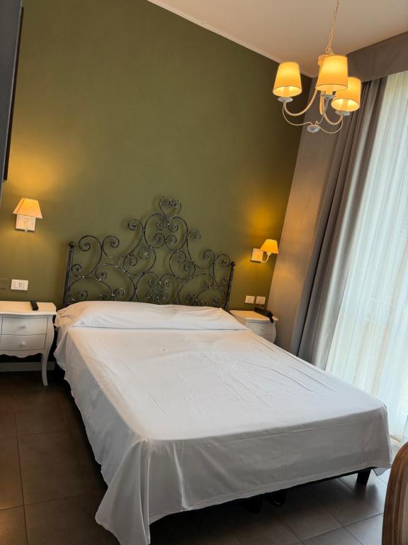 a bedroom with a white bed and a chandelier at Boutique Hotel Washington Milano - JCUBE HOTELLERIE in Milan