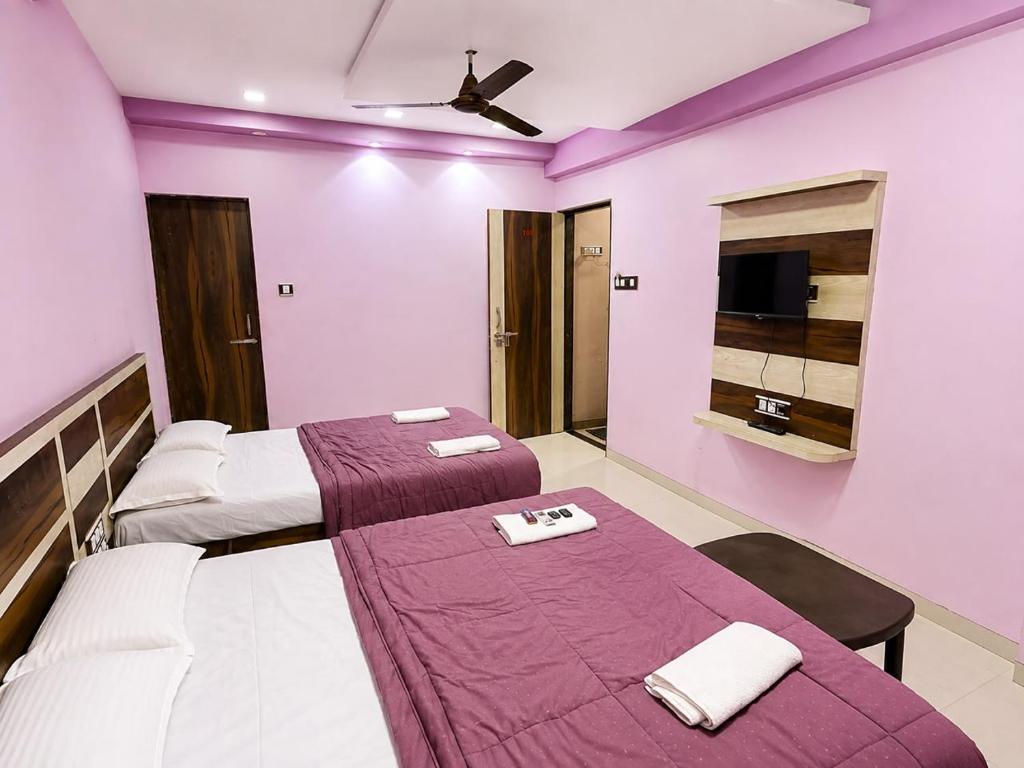 two beds in a room with purple walls at Sunset View in Mahabaleshwar