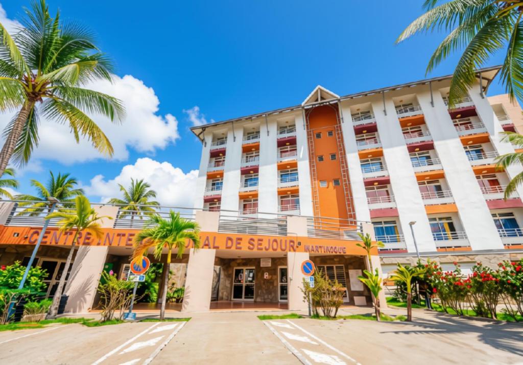 a hotel with palm trees in front of it at Centre International de Sejour in Fort-de-France