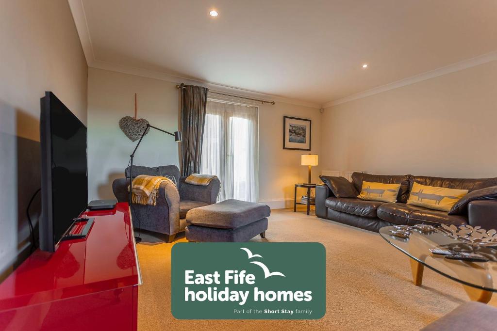 a living room with a couch and a tv at Links Lodge - Blacklaws Steading in Anstruther