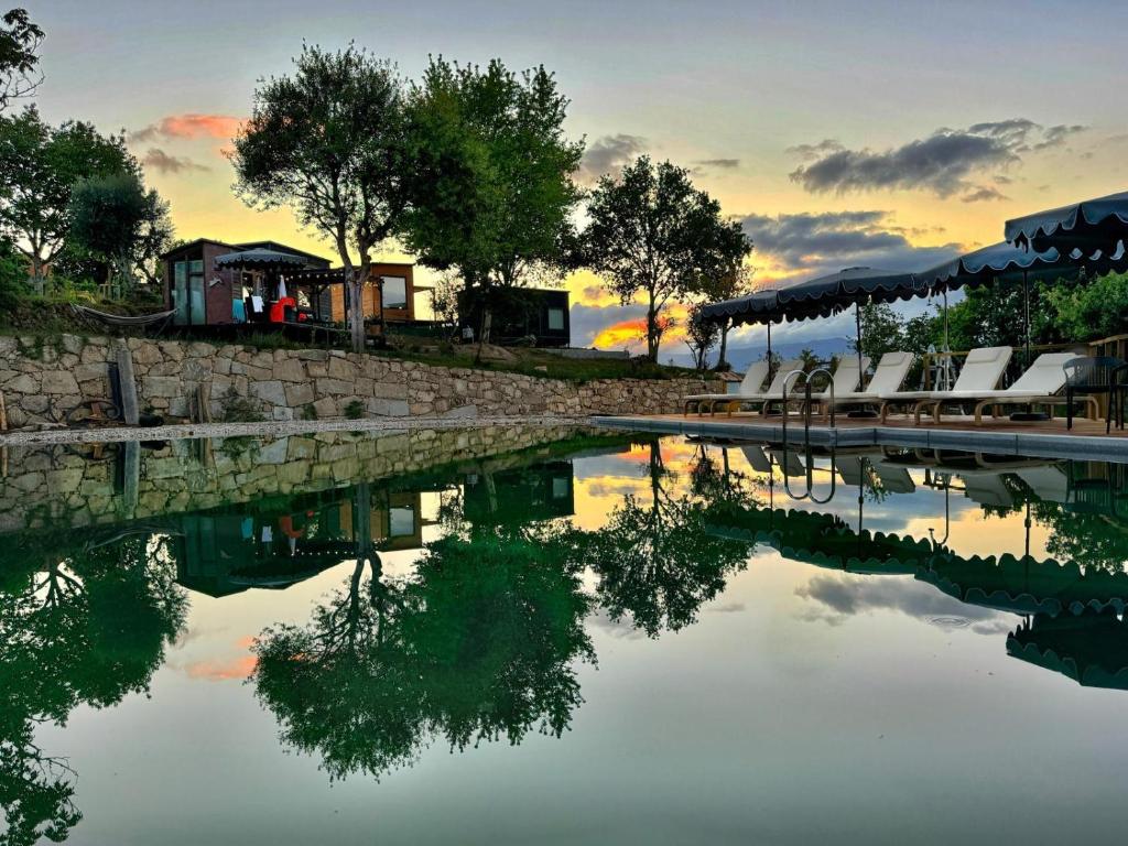 a pool of water with chairs and a sunset at Tiny Escape in São Miguel do Mato