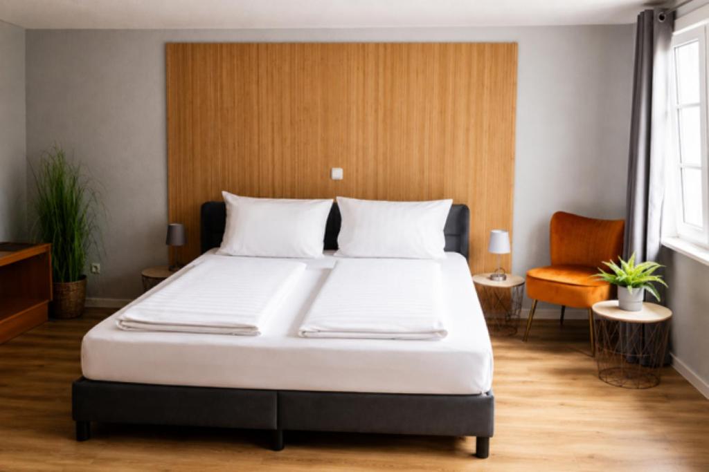 a bedroom with a large bed and a chair at Dahlbrucher Hof in Hilchenbach