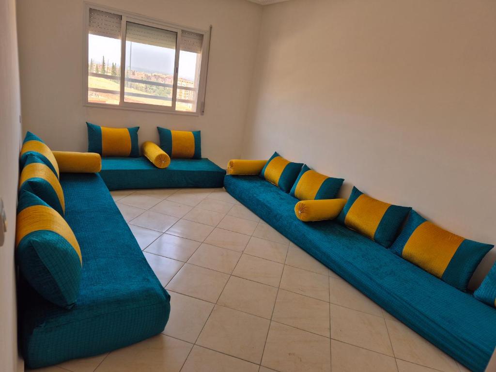 a living room with blue couches and yellow pillows at Zohor atlas in Beni Mellal