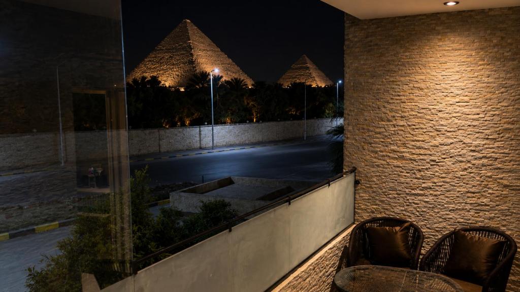 two chairs sitting on a balcony at night with pyramids at Dar Pyramids Boutique in Cairo