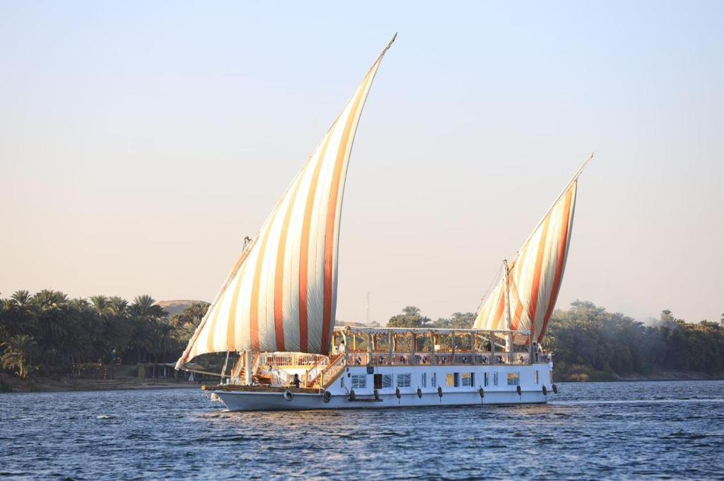 a sailboat with people on it on the water at Three pyramids Dahabiya in Esna