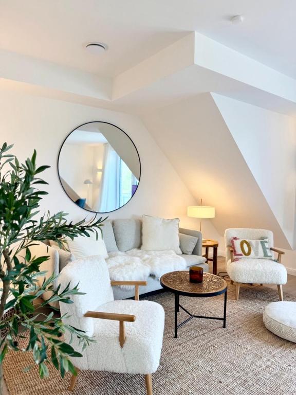 a living room with a couch and a mirror at Vollmöblierte hochwertige neue Apartments in Klevendeich