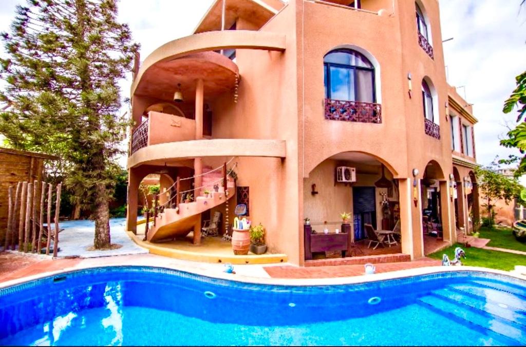 a house with a swimming pool in front of a house at Maison Sahel - African Art & Coastal Serenity in Dakar