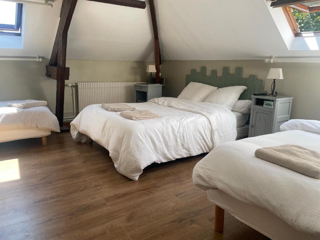 a bedroom with two beds with white sheets and wood floors at Gîtes chez julie in Beaucamps-Ligny