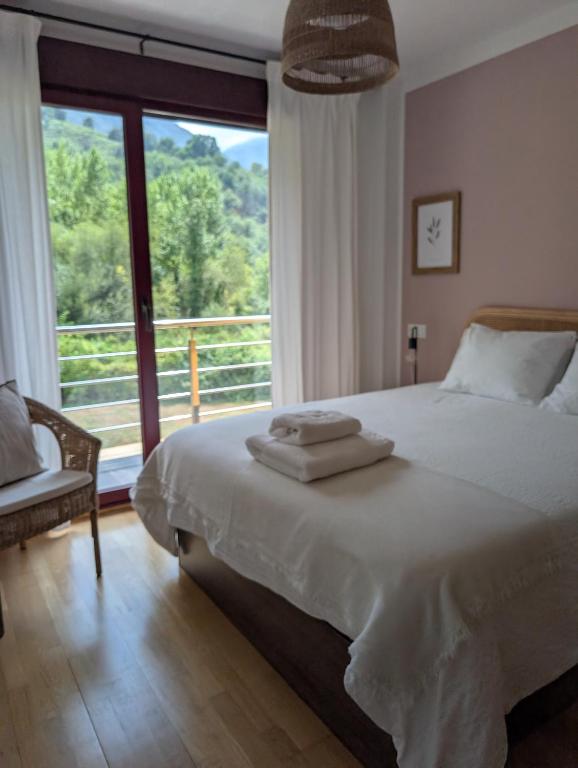 a bedroom with a large bed and a large window at Apartamento LLAR DEL CARES in Arenas de Cabrales