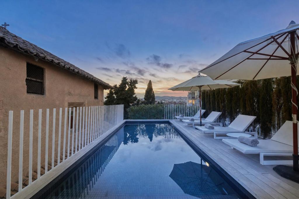 a swimming pool with lounge chairs and an umbrella at Convent de la Missio - Grand Luxury Boutique hotel, Adults Only in Palma de Mallorca