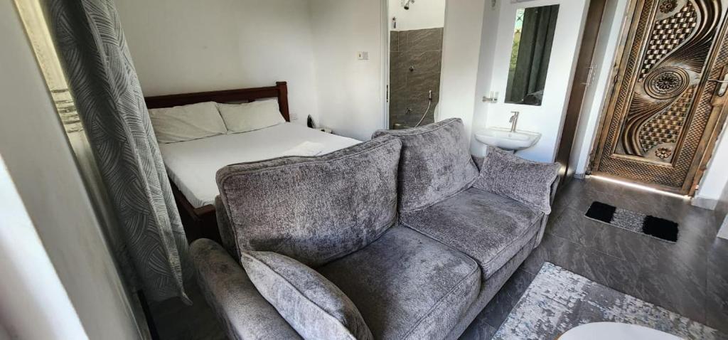 a bedroom with a couch and a bed and a mirror at Tulia Stays in Mtwapa