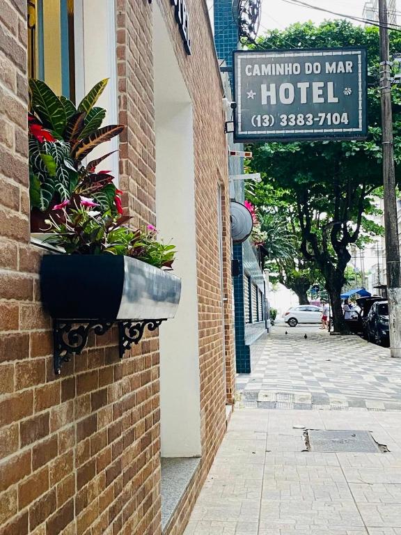 a hotel sign on the side of a brick building with plants at Caminho do Mar Hotel in Guarujá