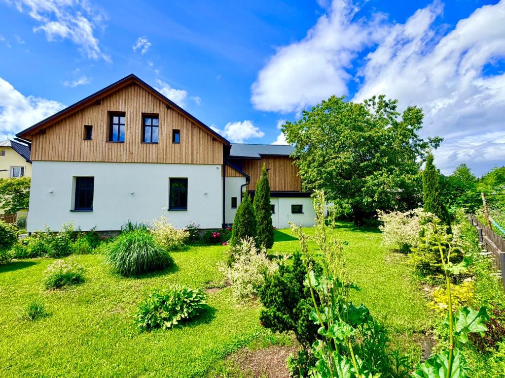 a large white house with a grass yard at Apartmány CHATTA in Horní Maršov