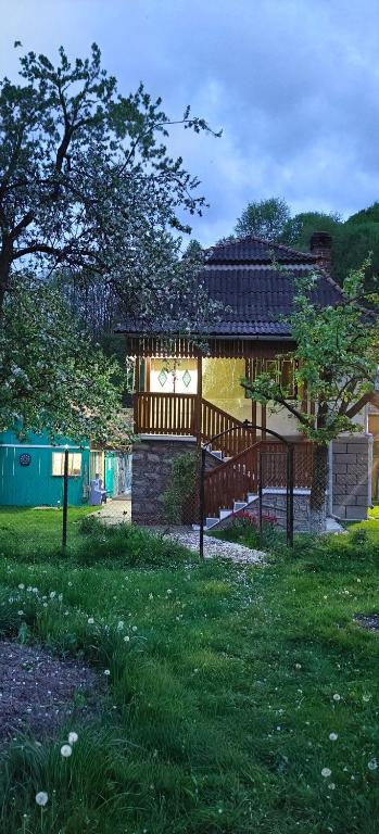 a house with a deck in a yard at La Umbra Muntilor Traditional House in Ocoliş