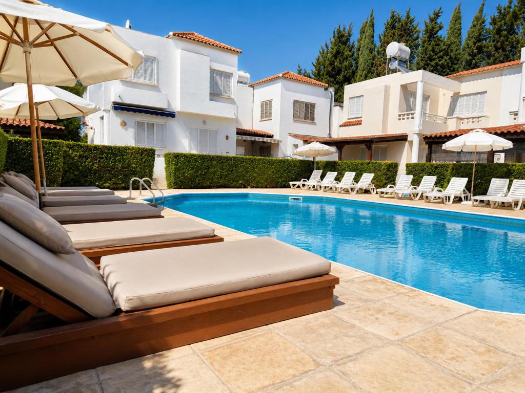a swimming pool with chaise lounge chairs and an umbrella at Nerina Townhouse By Staycom in Paphos