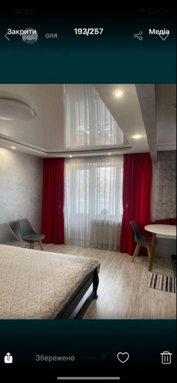 a bedroom with a bed and red curtains and a table at Vladimir City 60 in Volodymyr-Volynskyi
