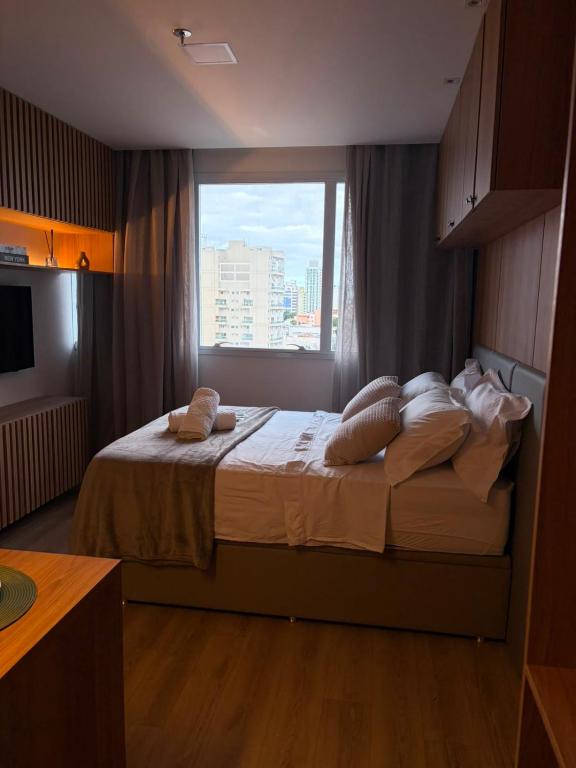 a bedroom with a large bed with a window at Flat 503 - America in Campos dos Goytacazes