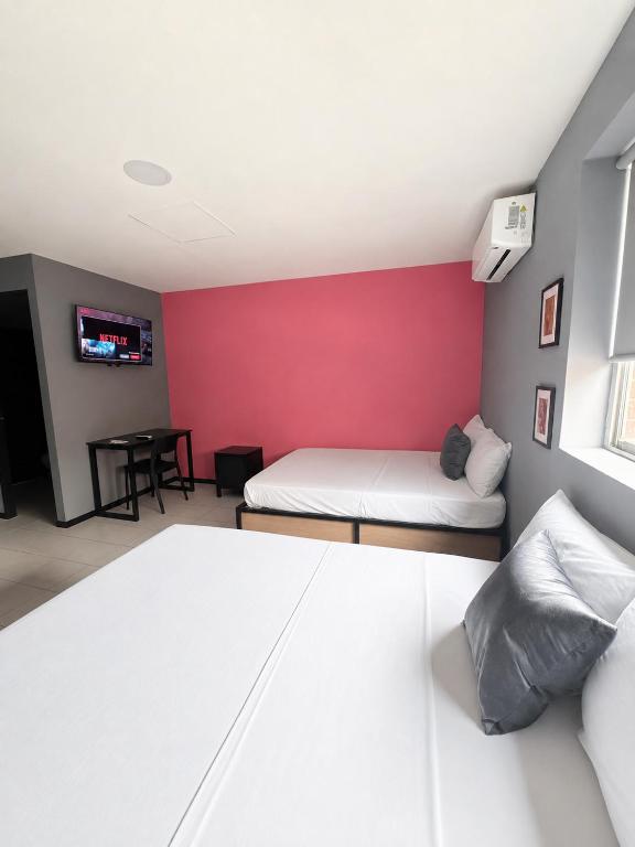 een slaapkamer met twee bedden en een rode muur bij Adhoc Macro in Monterrey