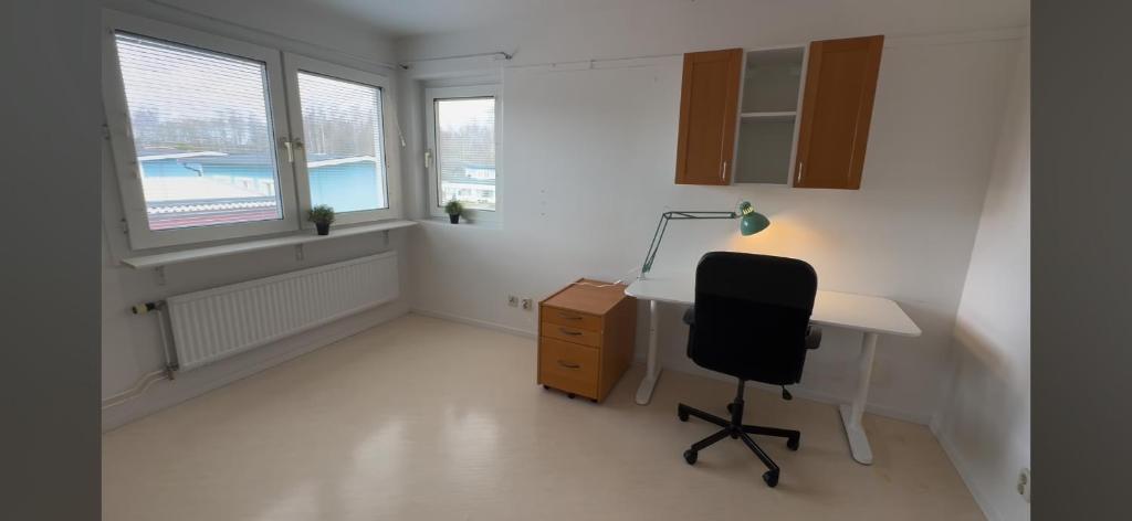 an office with a desk and a chair and windows at Mangatan 2 in Borlänge