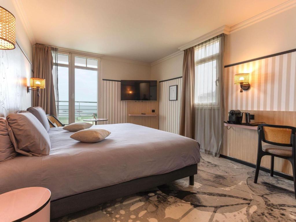 a hotel room with a large bed and a table at Mercure Granville Le Grand Large in Granville