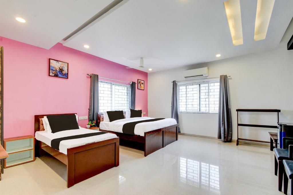 two beds in a room with pink walls at Super Hotel O SRI NIRVANA PLAZA in Gachibowli