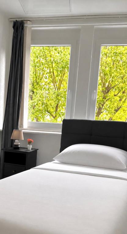 a bedroom with a white bed and two windows at Relax Apartment Backnang in Backnang