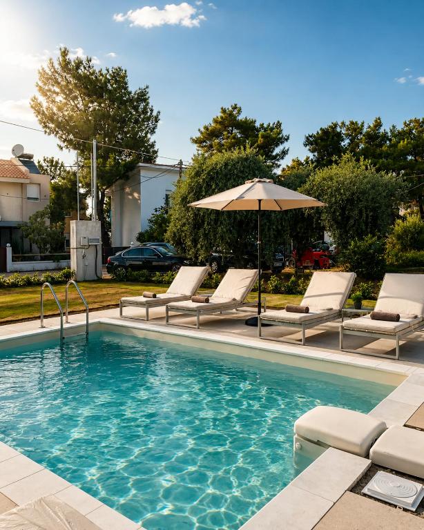 a swimming pool with lounge chairs and an umbrella at Minimal Suites in Skala Rachoniou