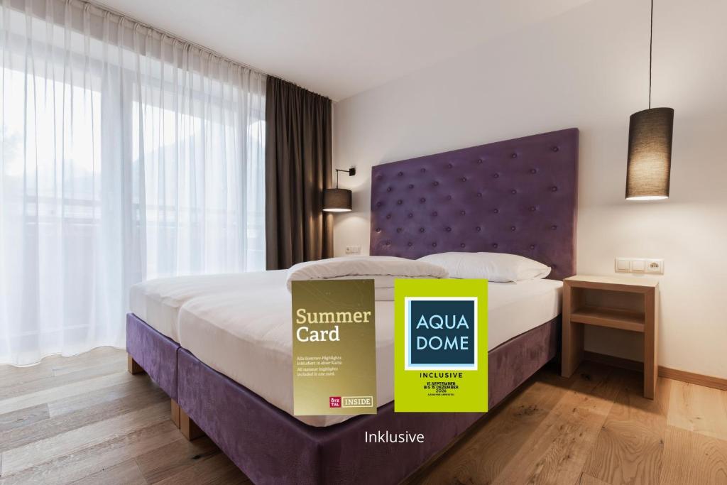 ein Schlafzimmer mit einem Bett mit lila Kopfteil in der Unterkunft Hotel Bergwelt in Längenfeld