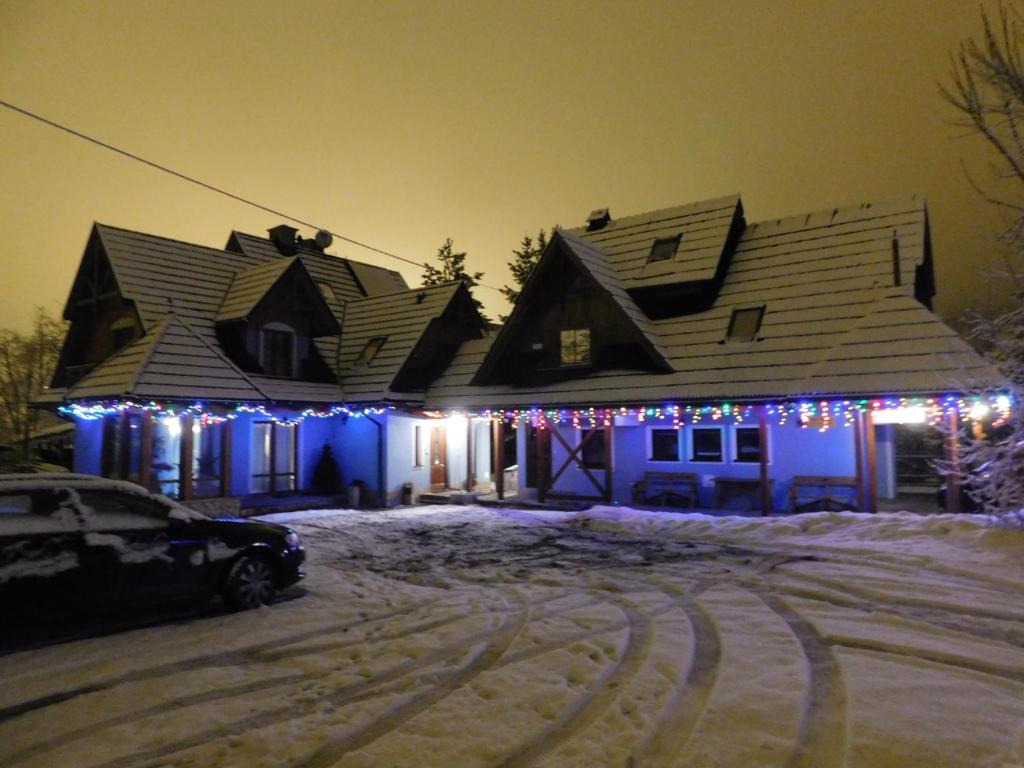 a house decorated with christmas lights in the snow at Pokoje i Apartamenty u Architekta in Czarna Góra