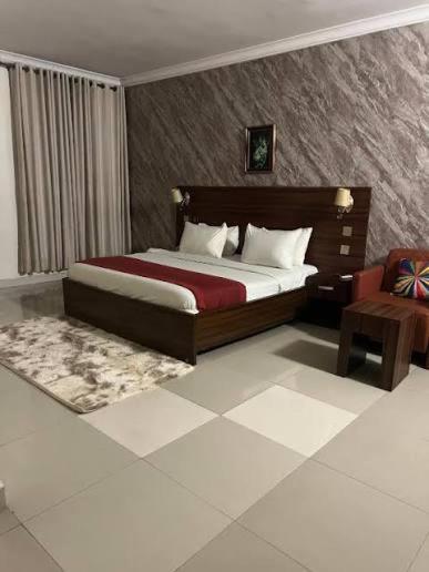 a bedroom with a large bed and a chair at POSH HOTEL iSLAND in Victoria Island