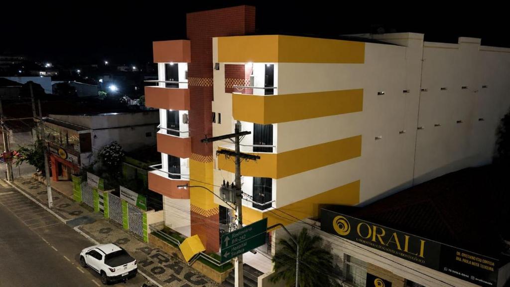 a yellow and white building with a white car on a street at Araújo Hotel in Itaberaba